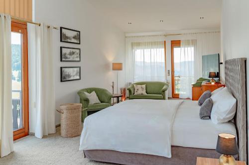a bedroom with a large white bed and chairs at Bergseele Privat- & Retreathotel Schwarzwald in Todtnauberg