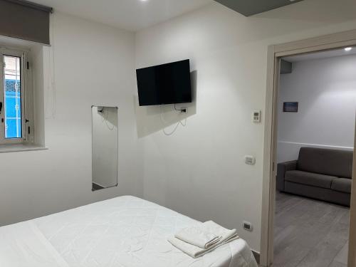 a white room with a bed and a television on the wall at al mare casa vacanza in Rossano Stazione