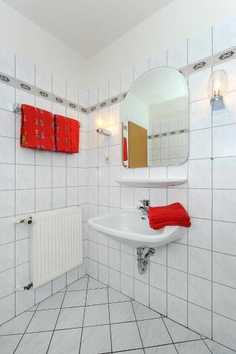 a white bathroom with a sink and a mirror at Haus Hafenromantik in Neuharlingersiel