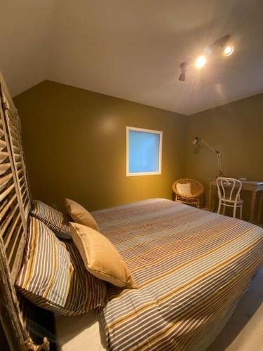 une chambre avec un lit avec des oreillers et une fenêtre dans l'établissement Gîte du Cap Romain, à Bernières-sur-Mer