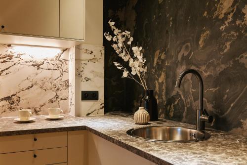 - un évier de cuisine avec un vase de fleurs sur un comptoir dans l'établissement Saint Lambert Suite - Duke Housing, à Paris