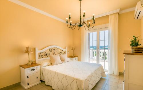 una camera da letto con un letto bianco e un lampadario di Villa Carmela a Baena