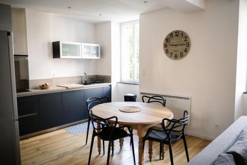 une cuisine avec une table et des chaises et une horloge au mur dans l'établissement Grand T3, plein centre, à Bagnères-de-Bigorre