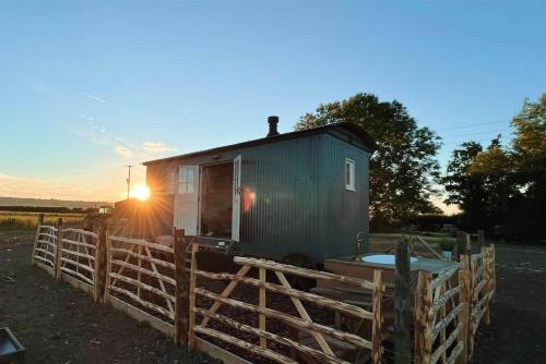 a tiny house on a fence with the sun setting at The Romney by Bloom Stays in Ashford