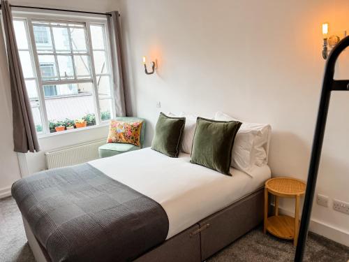 a bedroom with a bed with green pillows and a window at Dog and Whistle Pub in Hertford