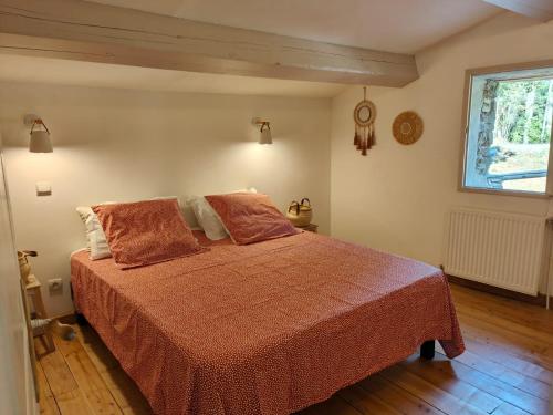 ein Schlafzimmer mit einem Bett mit orangefarbener Bettwäsche und einem Fenster in der Unterkunft Le Mas de la Rode in Saumane