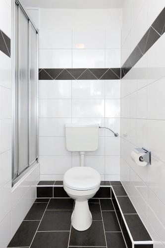 a white toilet in a bathroom with black and white tiles at Haus Hafenromantik in Neuharlingersiel
