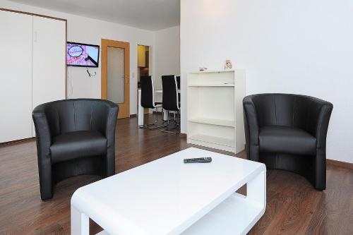 two black chairs and a white table in a room at Haus Hafenromantik in Neuharlingersiel