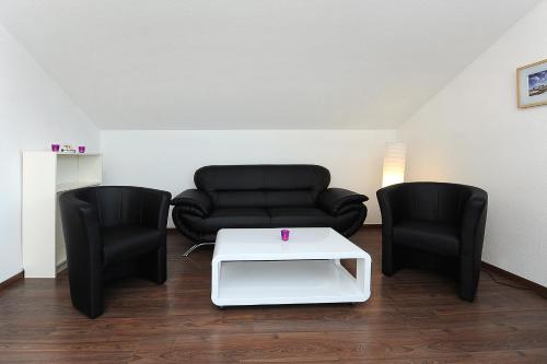 a living room with a couch and two chairs at Haus Hafenromantik in Neuharlingersiel