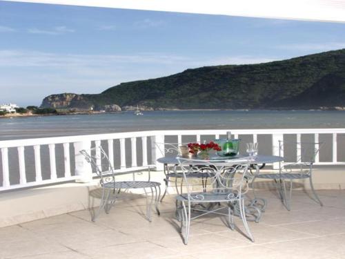 a table and chairs on a balcony overlooking the water at Isola Bella Guest House in Knysna