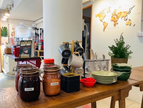 a wooden table with jars and plates on it at Unplugged at Bangrak Design Hostel in Bangkok