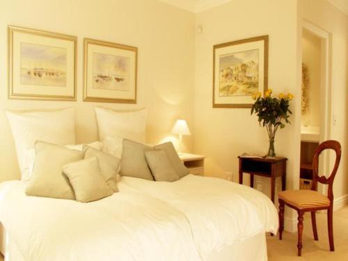 a bedroom with a white bed and a table and a chair at Isola Bella Guest House in Knysna