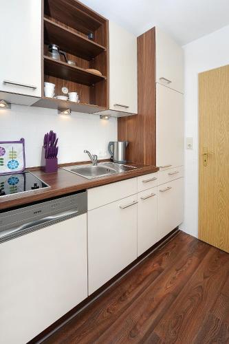 a kitchen with white cabinets and a sink at Haus Hafenromantik in Neuharlingersiel