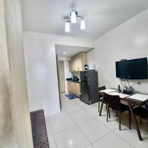 a kitchen and dining room with a table and a television at De Luxe, Standard and Studio Suites -The Breeze Residences-close to Airport,Mall of Asia, US Embassy in Manila