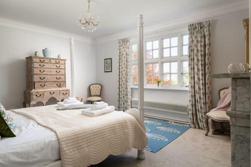 ein Schlafzimmer mit einem Bett, einer Kommode und einem Fenster in der Unterkunft Gresham Hall - Norfolk Cottage Agency in Norwich