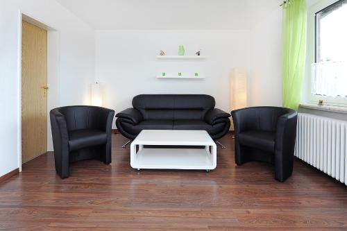 a living room with two chairs and a couch and a table at Haus Hafenromantik in Neuharlingersiel