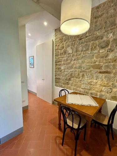 a dining room with a table and chairs and a stone wall at I Casaloni in Panzano