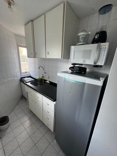 Una pequeña cocina con nevera y microondas. en Flat encantador beira mar na Barra . Em frente a praia! No Circuito do Carnaval de Salvador!, en Salvador