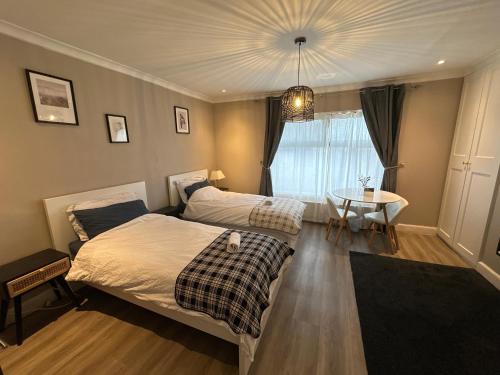 a bedroom with two beds and a table and a window at Park Terrace Family Room in Glastonbury