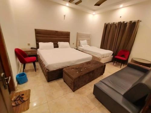 1 Schlafzimmer mit 2 Betten, einem Schreibtisch und Stühlen in der Unterkunft HOTEL DAY IN Empouriem in Lahore