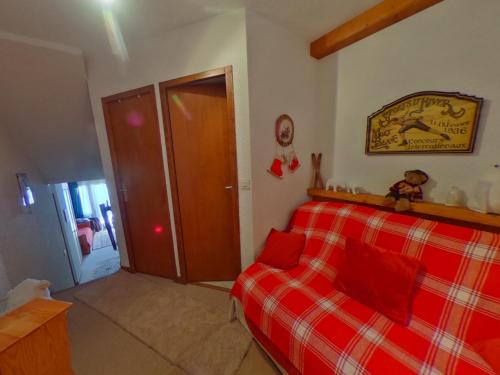 a bedroom with a red plaid bed and a door at Studio lumineux avec balcon sud, plein cœur de La Tania, skis aux pieds - FR-1-513-43 in La Tania