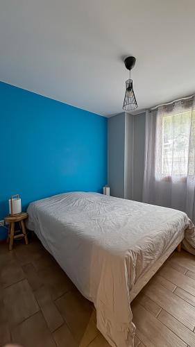 une chambre avec un grand lit avec un mur bleu dans l'établissement Montricher karellis, à 5 min de St Jean de Maurienne, à Montricher-Albanne