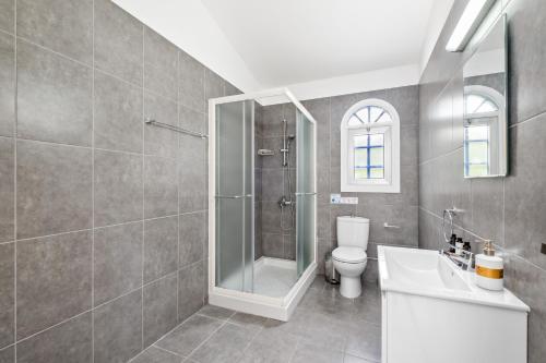 a bathroom with a shower and a toilet and a sink at Ivy Blue Villa by Nomads - Short Walk to Coral Bay in Peyia