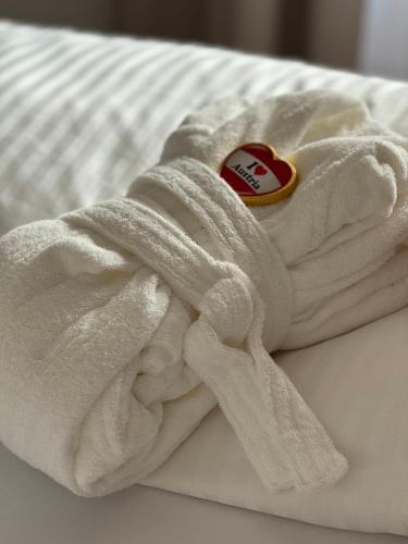 a white towel with a heart on it on a bed at Alpin Apartments am Dorfbrunnen JUNIOR SUITE in Steinach am Brenner