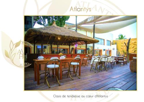 a restaurant with a table and chairs and an umbrella at Hotel l'ATLANTYS in Yopougon-Attié