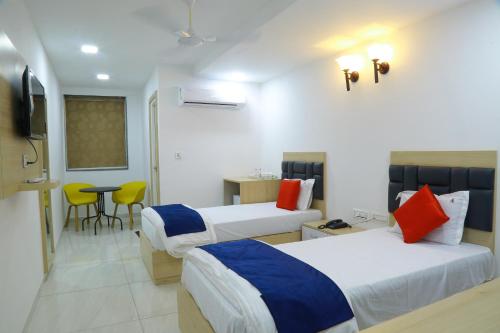 a hotel room with two beds and a table at The Balcony Suites I Gachibowli in Hyderabad