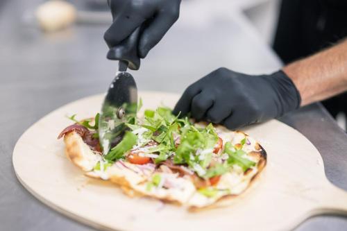 a person cutting a pizza with a pizza cutter at Inselhotel Rügen in Göhren