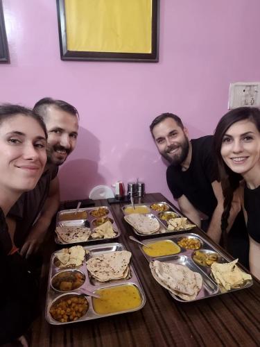 a group of people sitting around a table with food at Azure Family Paying Guest House in Varanasi