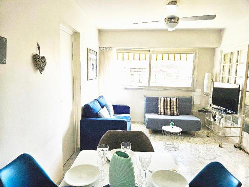Una sala de estar con una mesa y un sofá azul. en Le 66 Carnot, en Cannes