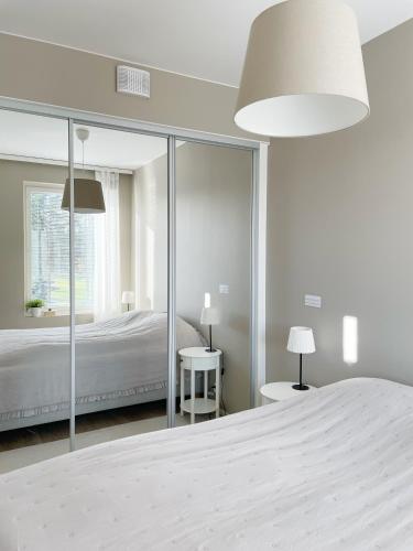 a white bedroom with a bed and a large mirror at Sunny Beach Apartment Hiekkasärkät Kalajoki in Kalajoki