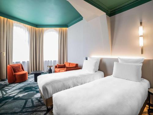 Pokój hotelowy z 2 łóżkami i pomarańczowym krzesłem w obiekcie Rezydent Hotel Sopot - MGallery Collection w mieście Sopot