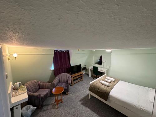 a hotel room with a bed and chairs and a television at The George Hotel in Battle