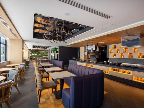 a restaurant with tables and chairs and a kitchen at Novotel Nara in Nara