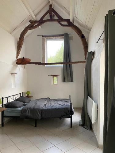 a bedroom with a bed in a room with a window at Charmante maison in Beaumont-Pied-de-Boeuf