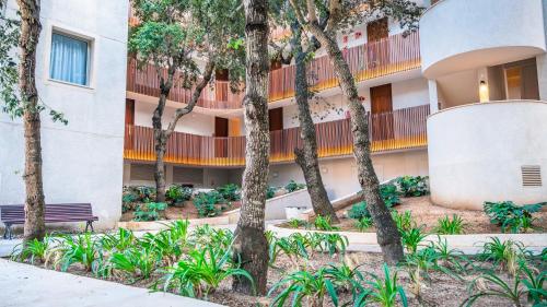 a building with trees and a bench in front of it at Canyamel Park Hotel & Spa - 4* Sup - Adults only (+16) in Canyamel