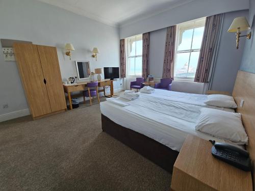 a hotel room with a large bed and a desk at The Burlington Hotel in Eastbourne