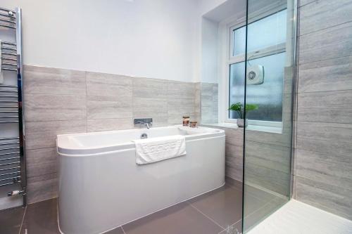 a bathroom with a tub and a glass shower at River View Large House In Afan Forest Bike Park By StayStaycations in Port Talbot