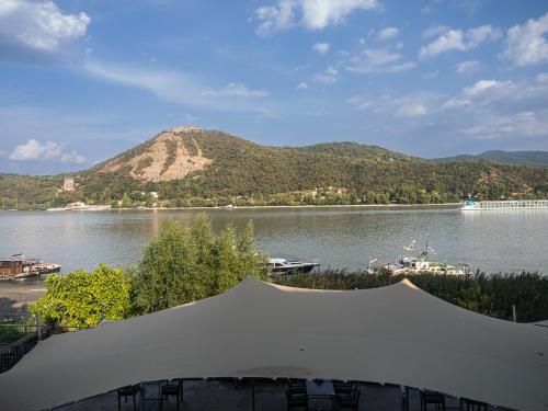 a view of a lake with a tent and a mountain at Vitrin Panzió in Nagymaros