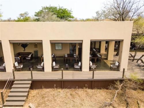 a house with a deck with chairs and tables at Honeyguide Tented Safari Camps - Mantobeni in Manyeleti Game Reserve