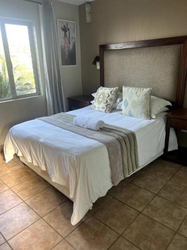 una habitación con una cama grande con sábanas y almohadas blancas en 58 Chakas Rock Chalets, en Ballito