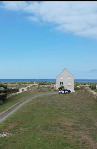 une maison blanche avec une voiture garée dans un champ dans l'établissement Maison posée sur la plage, à La Turballe