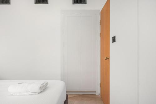 a bedroom with a bed with white sheets and a door at pisgat shoresh in Shoresh
