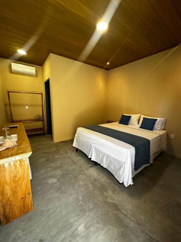 une chambre avec un grand lit dans une pièce dans l'établissement Pousada Oiti, à Barrinha