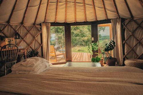 a bedroom with a bed and a large window at Nature Cabins Hiigher Farm in Ditcheat