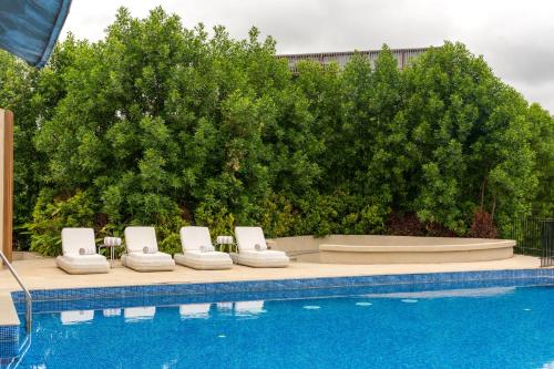 a row of lounge chairs next to a swimming pool at ORO The Estates, Nandi Hills in Nandigunda