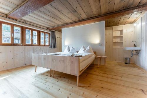 a bedroom with a large bed in a room with wooden floors at POORT A POORT Dorfhotel in Grengiols
